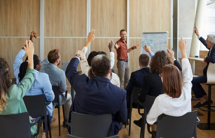 Young,Colleagues,Raising,Hands,To,Ask,Questions,During,Business,Meeting