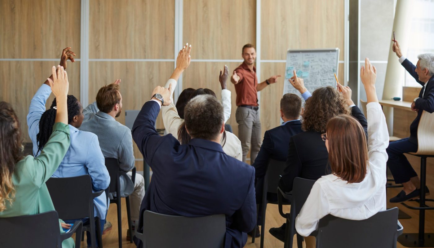 Young,Colleagues,Raising,Hands,To,Ask,Questions,During,Business,Meeting